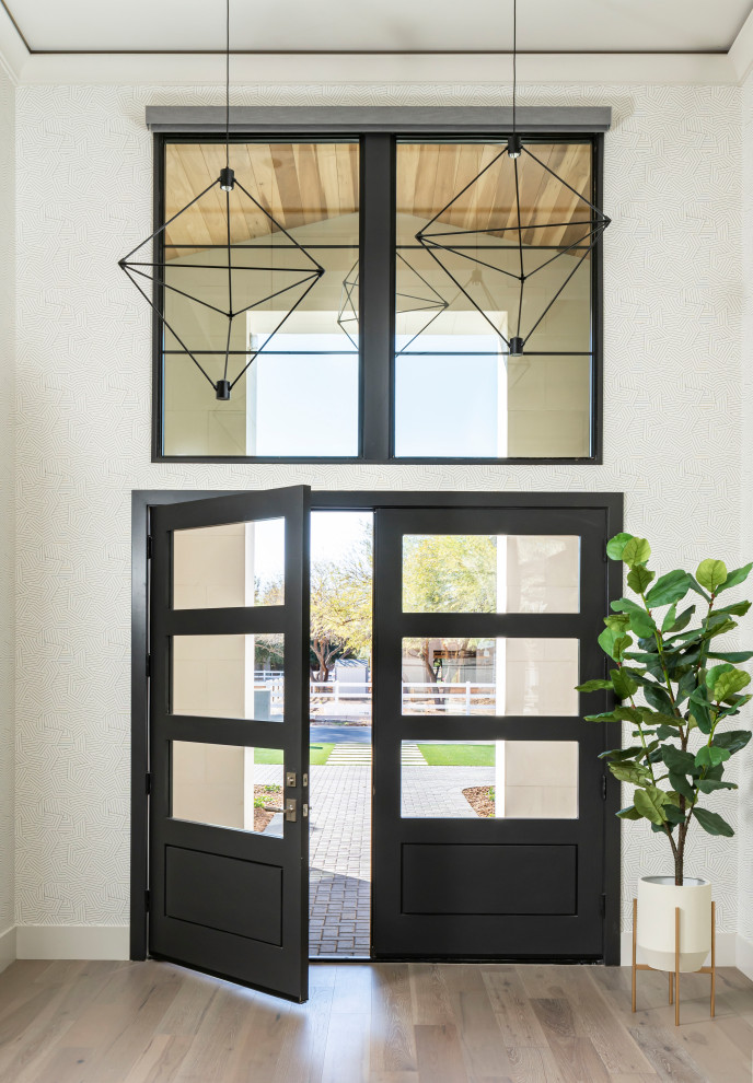 Diseño de puerta principal tradicional renovada extra grande con paredes blancas, suelo de madera en tonos medios, puerta doble, puerta negra, suelo gris, bandeja y papel pintado