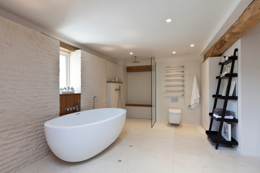 This is an example of a country bathroom in London with a freestanding tub, a wall-mount toilet, beige walls and a curbless shower.