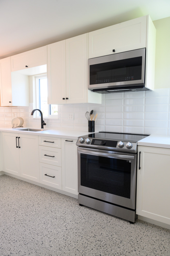 Photo of a medium sized classic u-shaped kitchen/diner in Vancouver with a single-bowl sink, recessed-panel cabinets, white cabinets, quartz worktops, white splashback, ceramic splashback, stainless steel appliances, terrazzo flooring, a breakfast bar, grey floors and white worktops.