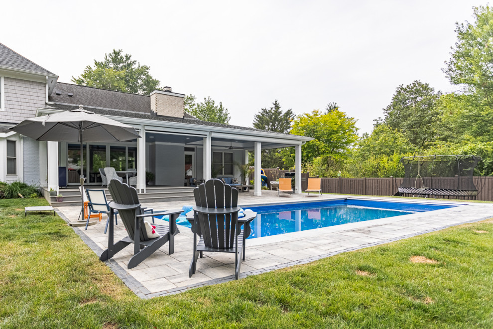 Diseño de piscina alargada clásica renovada grande rectangular en patio trasero con adoquines de hormigón