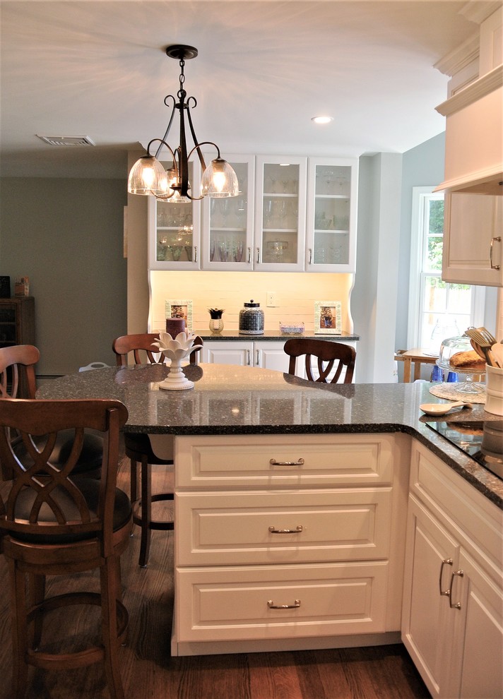 Inspiration for a transitional light wood floor eat-in kitchen remodel in Boston with an undermount sink, raised-panel cabinets, white cabinets, granite countertops, white backsplash, subway tile backsplash and stainless steel appliances