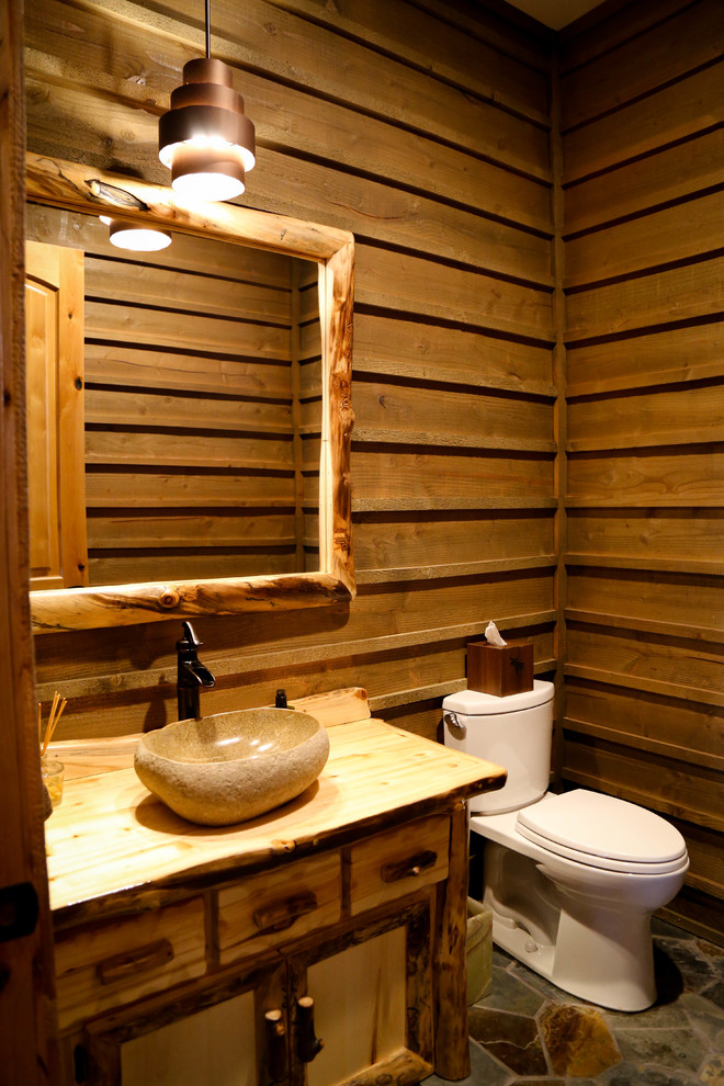 Photo of a country powder room in Salt Lake City with slate floors, wood benchtops, furniture-like cabinets, medium wood cabinets, a two-piece toilet, a vessel sink and multi-coloured floor.