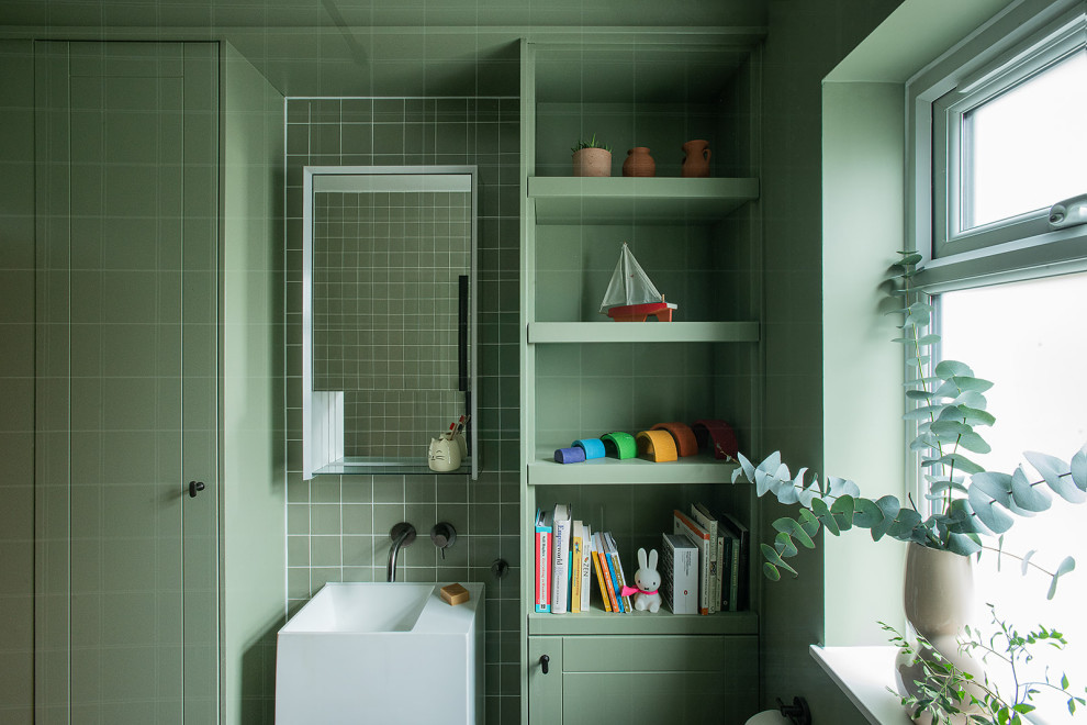 This is an example of a small traditional bathroom in London with a corner shower, a wall mounted toilet, green tiles, ceramic tiles, green walls, terrazzo flooring, a wall-mounted sink, wooden worktops, green floors, an open shower, green worktops and a single sink.