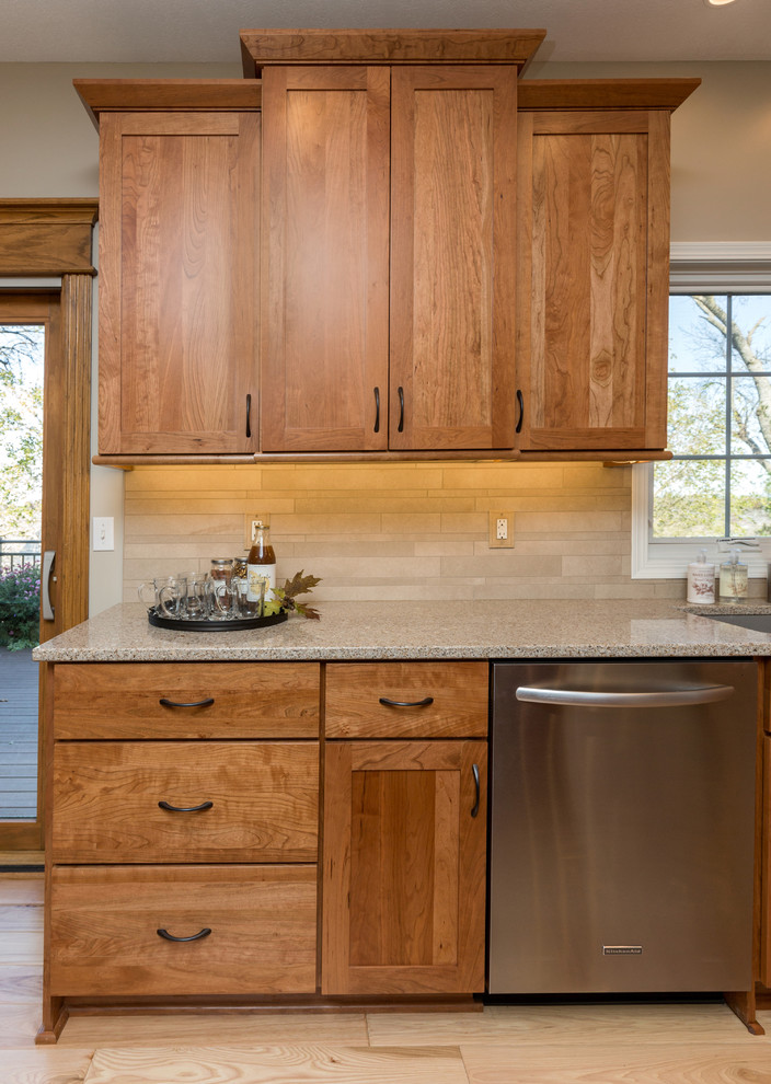 Mid-sized transitional l-shaped light wood floor open concept kitchen photo with an undermount sink, recessed-panel cabinets, medium tone wood cabinets, quartz countertops, beige backsplash, stone tile backsplash, stainless steel appliances and an island