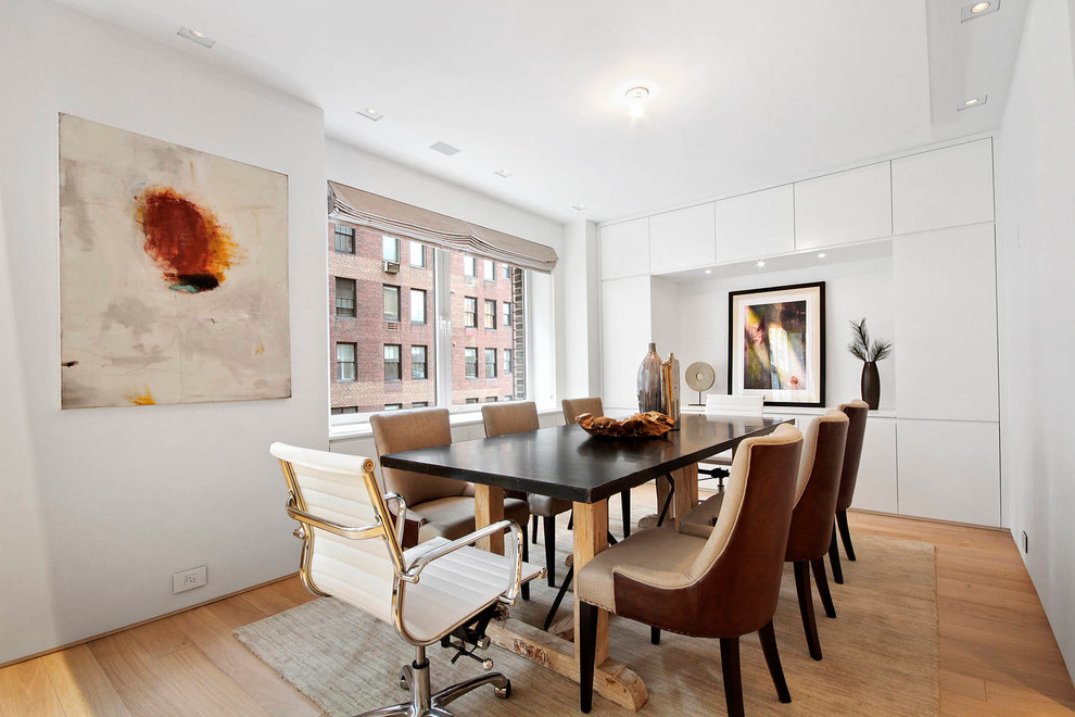 This is an example of a scandinavian dining room in New York with white walls and medium hardwood floors.