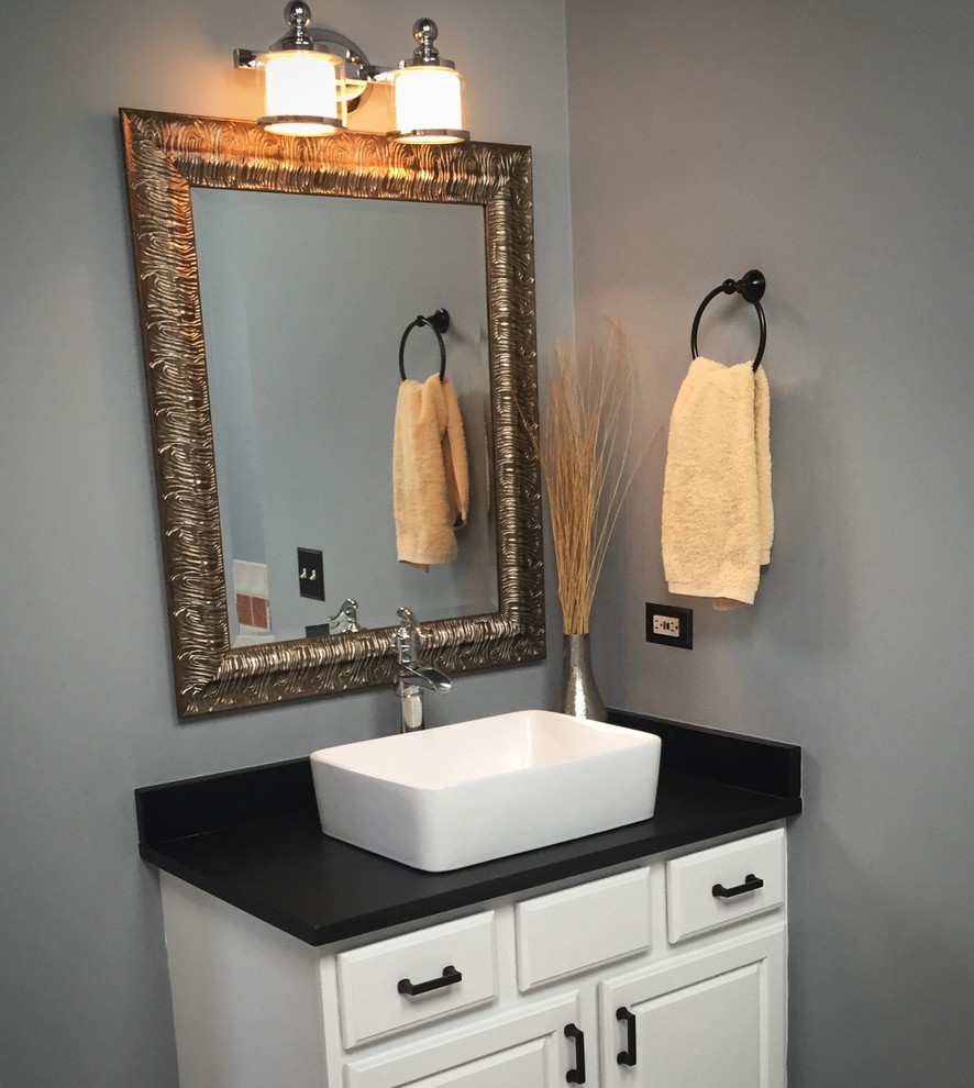 Mid-sized transitional master gray tile and ceramic tile ceramic tile corner bathtub photo in Chicago with raised-panel cabinets, black cabinets, a one-piece toilet, gray walls, a vessel sink and granite countertops