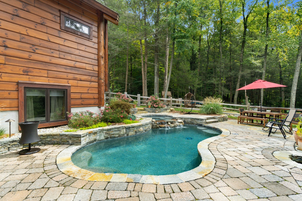 Esempio di una grande piscina chic personalizzata dietro casa con una vasca idromassaggio e pavimentazioni in cemento
