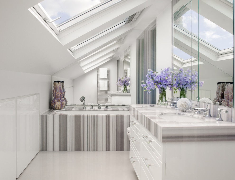 This is an example of a small transitional master bathroom in London with an alcove tub, white walls, an undermount sink, white floor and grey benchtops.