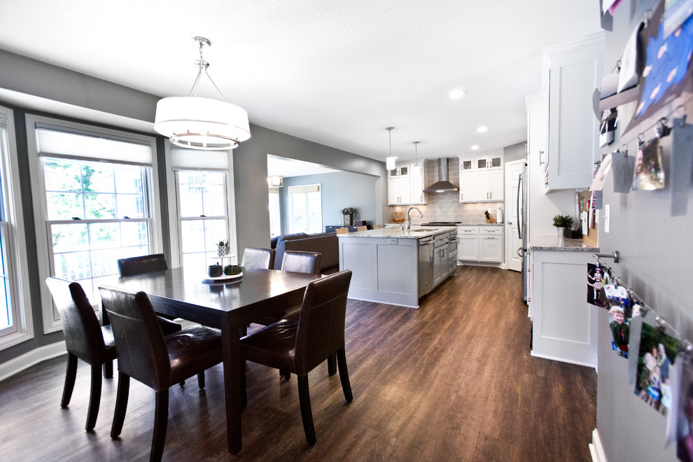 Eat-in kitchen - mid-sized transitional l-shaped vinyl floor and brown floor eat-in kitchen idea in Minneapolis with an undermount sink, shaker cabinets, white cabinets, granite countertops, gray backsplash, ceramic backsplash, stainless steel appliances, an island and multicolored countertops