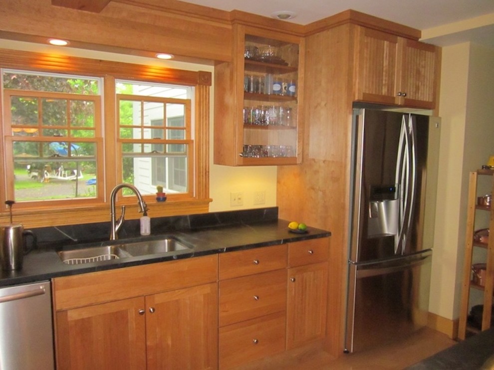 Mid-sized country l-shaped eat-in kitchen in New York with an undermount sink, shaker cabinets, light wood cabinets, soapstone benchtops, yellow splashback, stainless steel appliances, light hardwood floors and a peninsula.