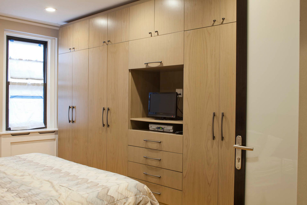 Inspiration for a large contemporary gender-neutral built-in wardrobe in New York with flat-panel cabinets and medium wood cabinets.