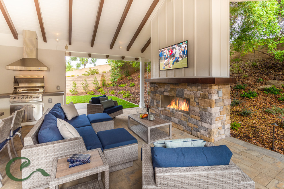 Inspiration for a mid-sized country backyard patio in Orange County with with fireplace, concrete pavers and a roof extension.