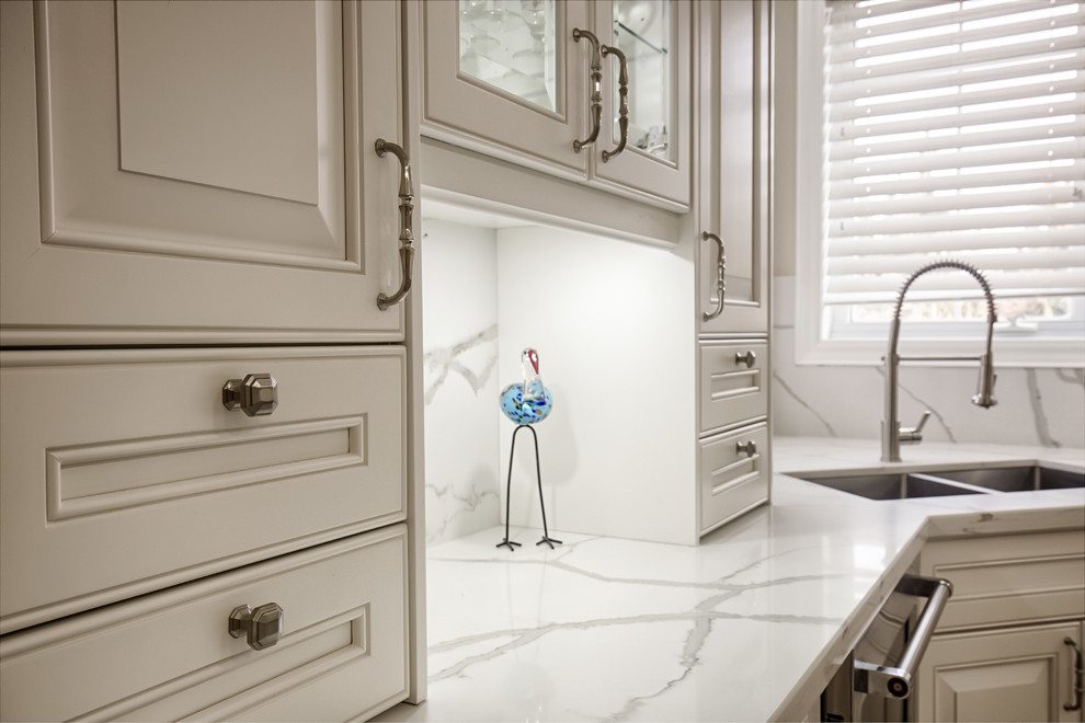 Large transitional u-shaped limestone floor and beige floor eat-in kitchen photo in Toronto with an undermount sink, raised-panel cabinets, white cabinets, marble countertops, white backsplash, marble backsplash, stainless steel appliances, an island and white countertops