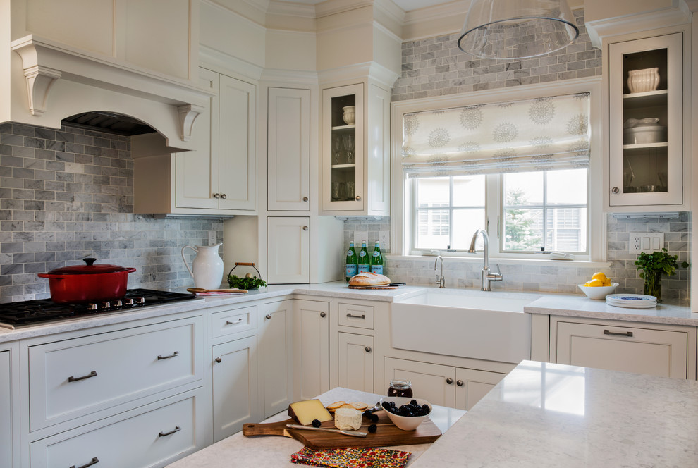 Inspiration for a mid-sized timeless l-shaped dark wood floor and brown floor open concept kitchen remodel in Boston with a farmhouse sink, beaded inset cabinets, white cabinets, marble countertops, gray backsplash, stone tile backsplash, stainless steel appliances and an island