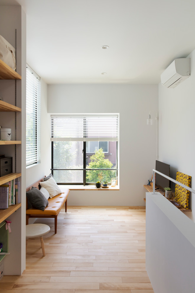 This is an example of a small contemporary living room in Tokyo with white walls, light hardwood floors, a freestanding tv and beige floor.