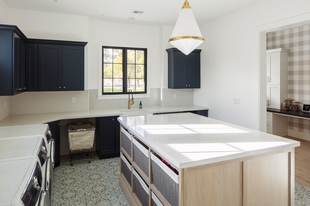 Photo of a large country dedicated laundry room in Phoenix with a farmhouse sink, shaker cabinets, blue cabinets, quartz benchtops, white walls, a side-by-side washer and dryer, white benchtop and multi-coloured floor.