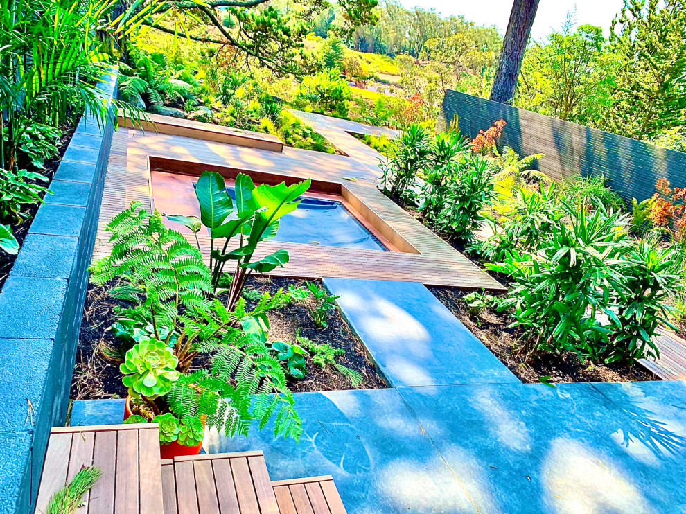 Idées déco pour un jardin arrière rétro de taille moyenne avec une terrasse en bois et une clôture en bois.