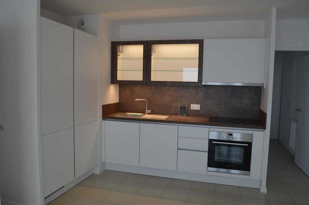 Mid-sized contemporary l-shaped open plan kitchen in Lyon with a single-bowl sink, flat-panel cabinets, white cabinets, laminate benchtops, brown splashback, stainless steel appliances, porcelain floors and no island.