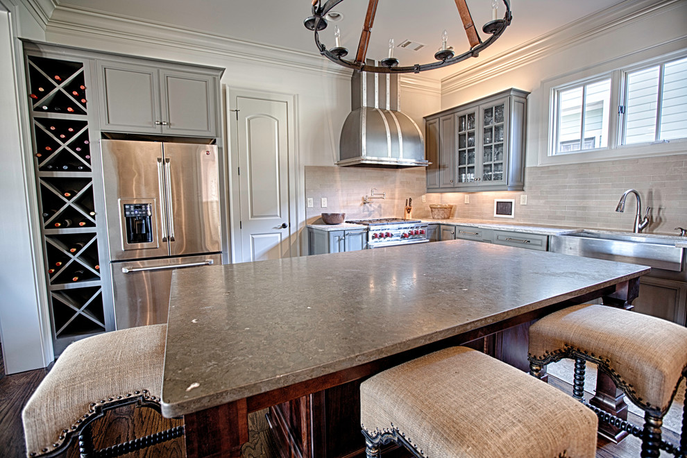 Open concept kitchen - large rustic u-shaped medium tone wood floor open concept kitchen idea in Birmingham with a farmhouse sink, flat-panel cabinets, gray cabinets, limestone countertops, beige backsplash, stone tile backsplash, stainless steel appliances and an island