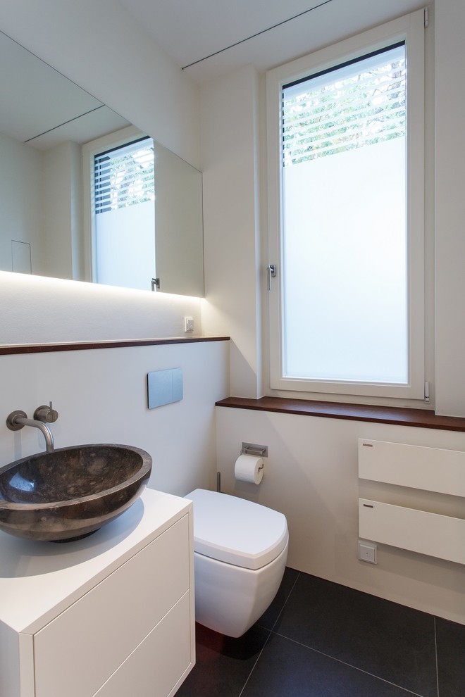 Design ideas for a mid-sized contemporary 3/4 bathroom in Other with flat-panel cabinets, white cabinets, a corner tub, a curbless shower, a two-piece toilet, white tile, marble, white walls, limestone floors, a vessel sink, wood benchtops, grey floor and an open shower.