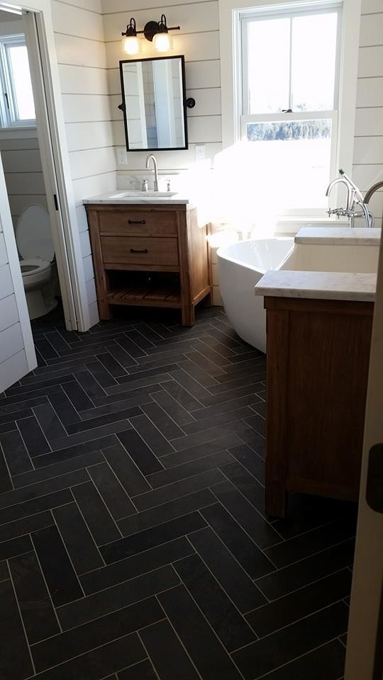 Photo of a mid-sized country master bathroom in Burlington with furniture-like cabinets, medium wood cabinets, a freestanding tub, a two-piece toilet, black and white tile, stone tile, beige walls, slate floors, an integrated sink and marble benchtops.