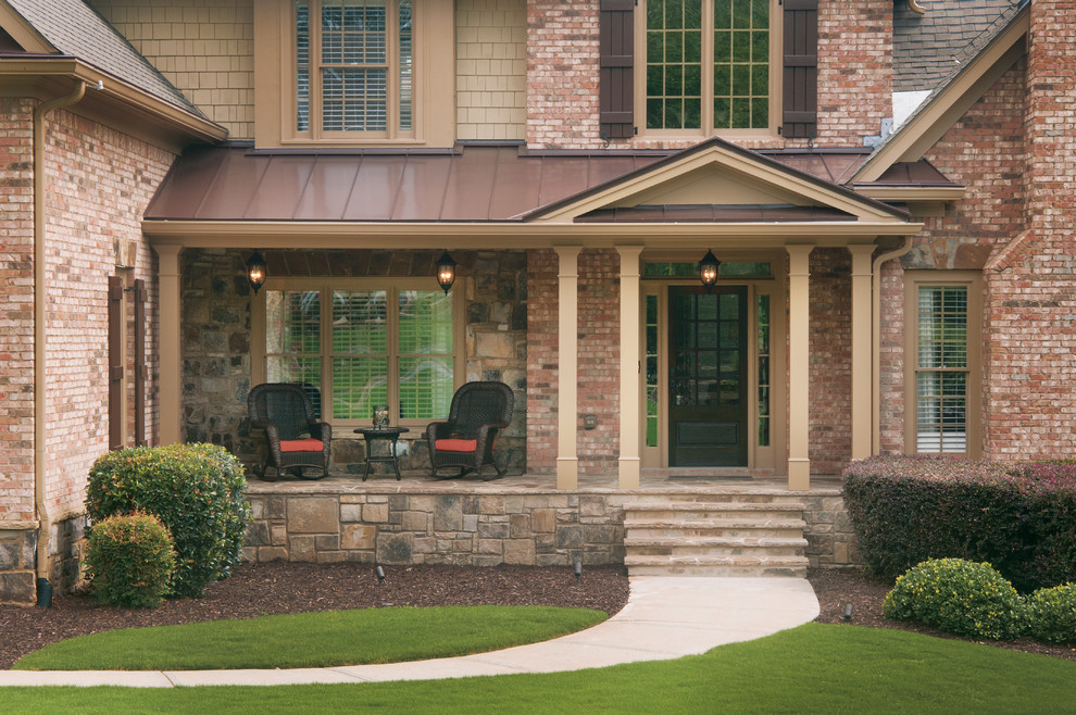 Photo of a mid-sized traditional front yard verandah in Atlanta with natural stone pavers and a roof extension.