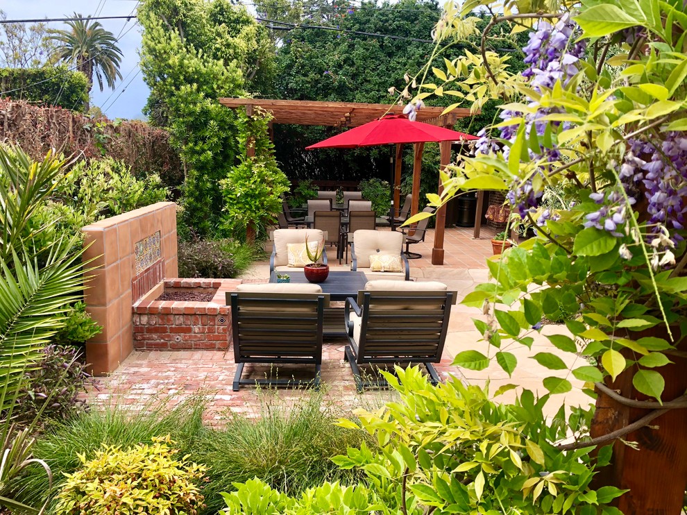 Design ideas for a mid-sized mediterranean backyard full sun xeriscape for spring in Los Angeles with a fire feature, brick pavers and a wood fence.