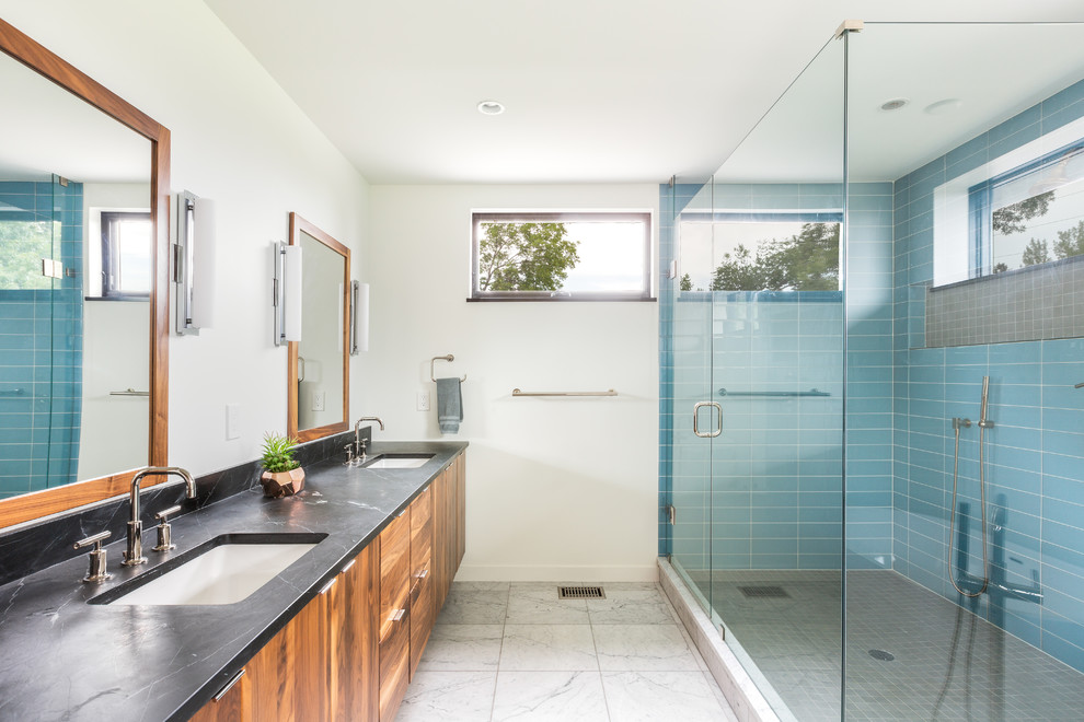 Design ideas for a midcentury master bathroom in Denver with medium wood cabinets, a freestanding tub, a double shower, blue tile, subway tile, white walls, mosaic tile floors, granite benchtops, black floor, a hinged shower door, black benchtops, a double vanity and a floating vanity.