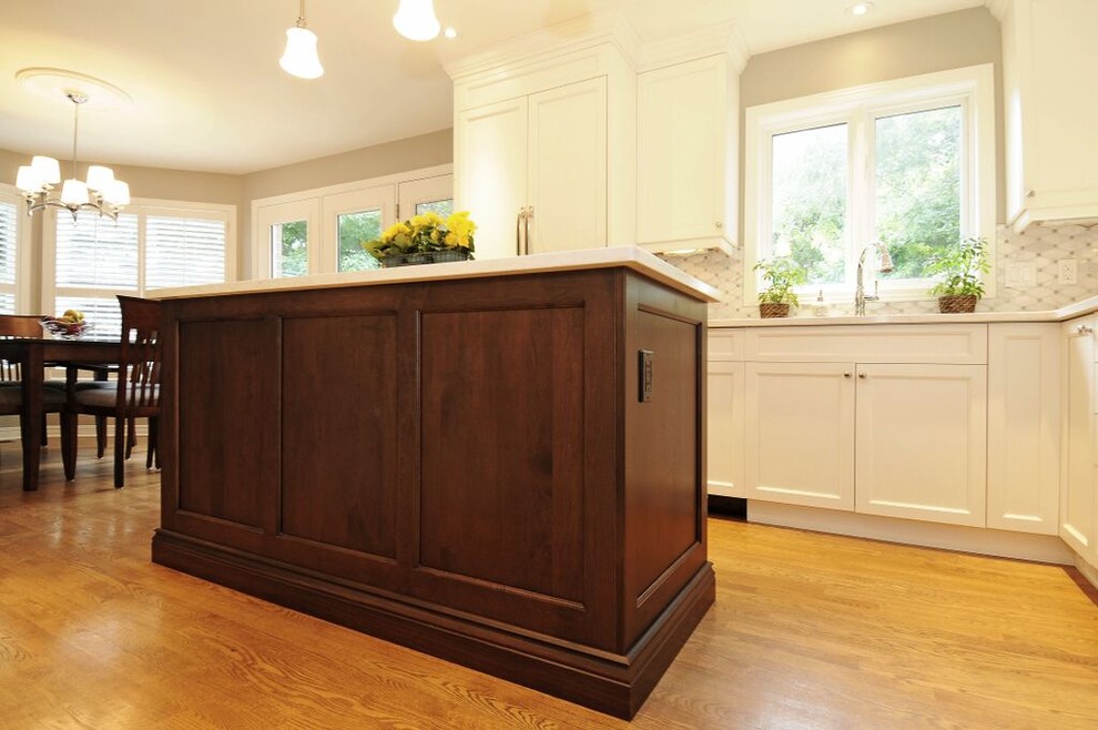 Mid-sized transitional l-shaped medium tone wood floor kitchen photo in Ottawa with a double-bowl sink, recessed-panel cabinets, white cabinets, quartz countertops, gray backsplash, stone tile backsplash, stainless steel appliances and an island