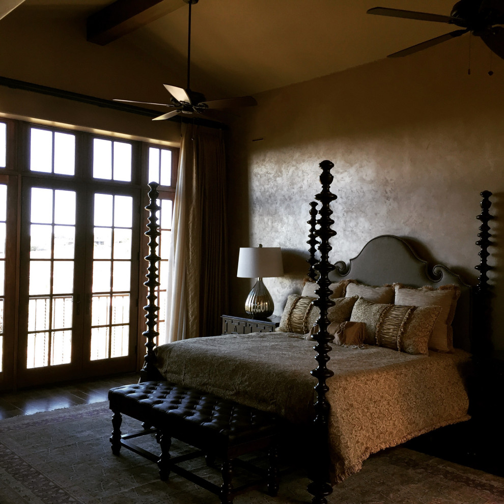 Cette photo montre une grande chambre parentale méditerranéenne avec un mur beige, un sol en bois brun, une cheminée standard et un manteau de cheminée en plâtre.