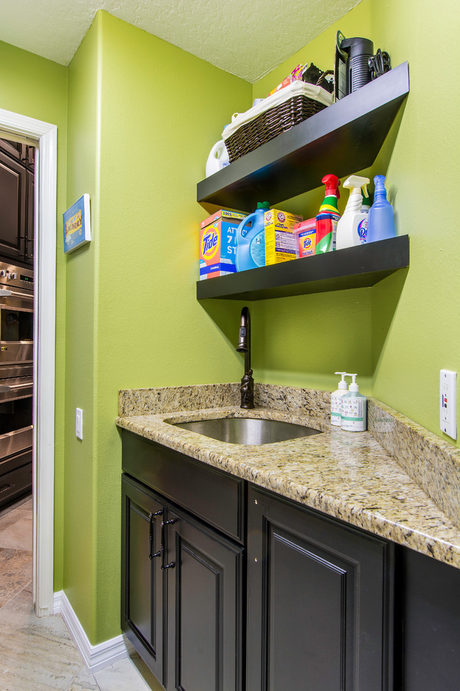 Inspiration for a small transitional galley laundry room in Tampa with an undermount sink, raised-panel cabinets, black cabinets, granite benchtops, green walls, porcelain floors and a side-by-side washer and dryer.