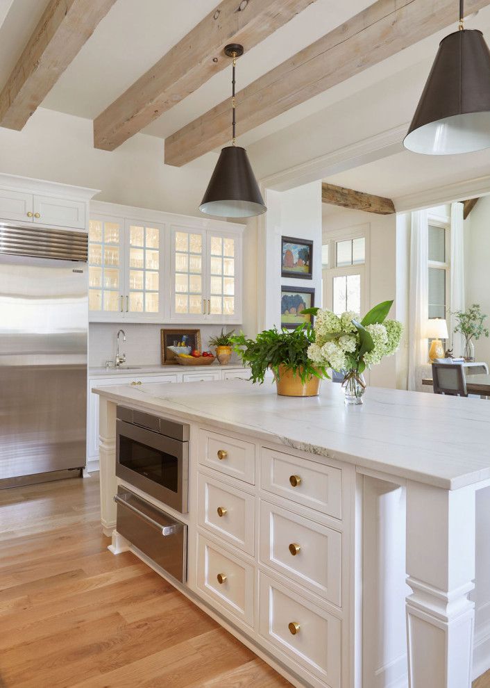 Example of a large transitional l-shaped medium tone wood floor eat-in kitchen design in Birmingham with a farmhouse sink, recessed-panel cabinets, white cabinets, stainless steel appliances and an island