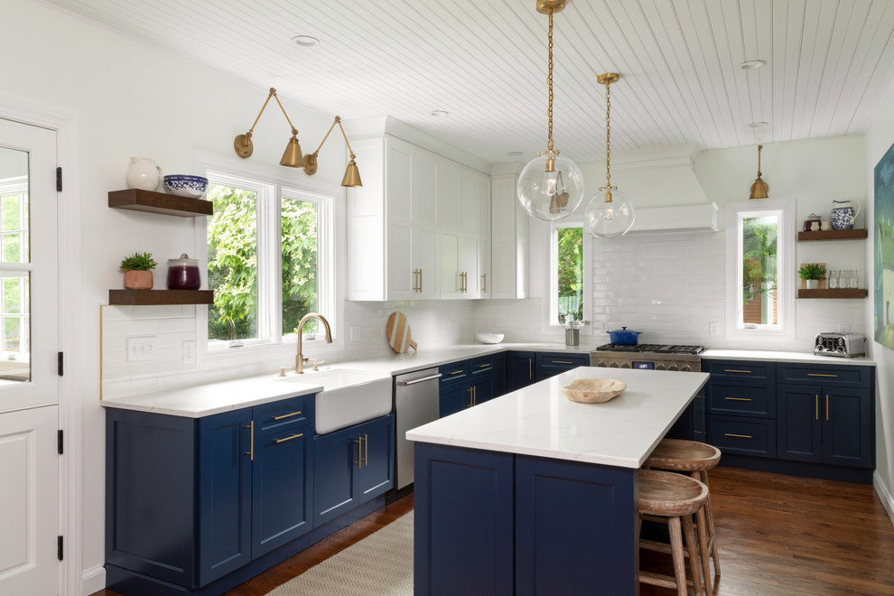 Inspiration for a large country l-shaped eat-in kitchen in Boston with a farmhouse sink, shaker cabinets, white cabinets, marble benchtops, white splashback, stainless steel appliances, medium hardwood floors, with island, brown floor, white benchtop and subway tile splashback.