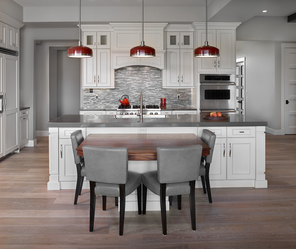 Large transitional l-shaped light wood floor and beige floor eat-in kitchen photo in Edmonton with a farmhouse sink, recessed-panel cabinets, white cabinets, quartz countertops, gray backsplash, matchstick tile backsplash, stainless steel appliances and an island