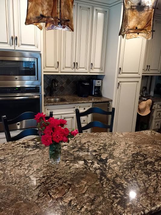 Example of a mid-sized transitional l-shaped medium tone wood floor and brown floor eat-in kitchen design in Birmingham with raised-panel cabinets, white cabinets, multicolored backsplash, stainless steel appliances, an island and a double-bowl sink