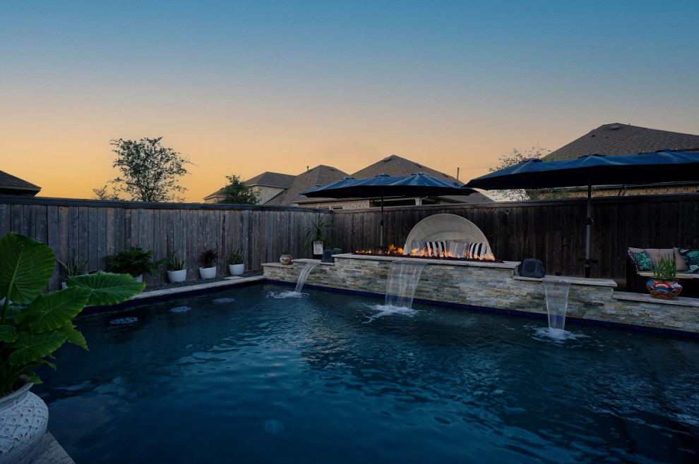 Idee per una piscina tropicale rettangolare di medie dimensioni e dietro casa con pavimentazioni in pietra naturale