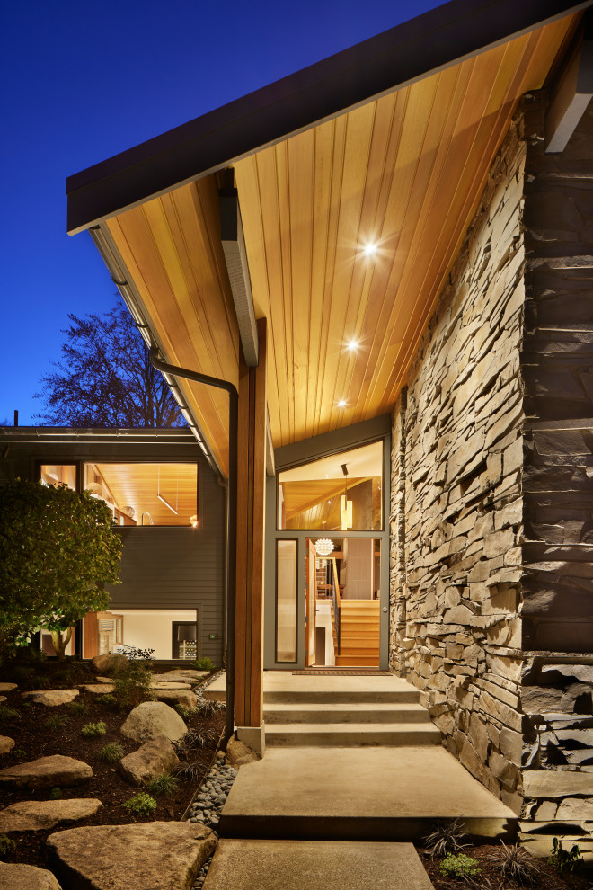 Mid-sized mid-century modern medium tone wood floor and vaulted ceiling entryway photo in Seattle with white walls and a medium wood front door