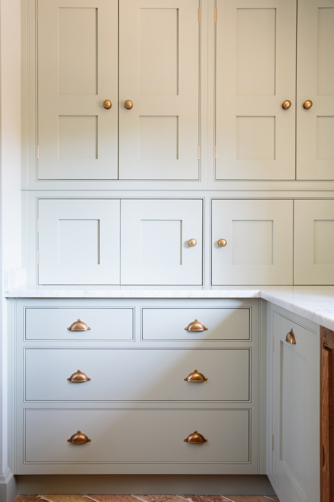 Foto di una piccola cucina classica con ante a filo, top in marmo, pavimento in mattoni e top grigio