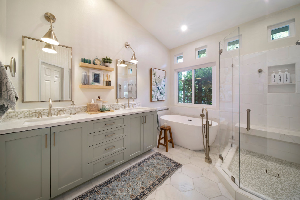 Inspiration for a mid-sized beach style master bathroom in Orange County with shaker cabinets, green cabinets, a freestanding tub, a corner shower, white tile, porcelain tile, beige walls, marble floors, an undermount sink, engineered quartz benchtops, white floor, a hinged shower door, white benchtops, a shower seat, a double vanity, a built-in vanity and vaulted.