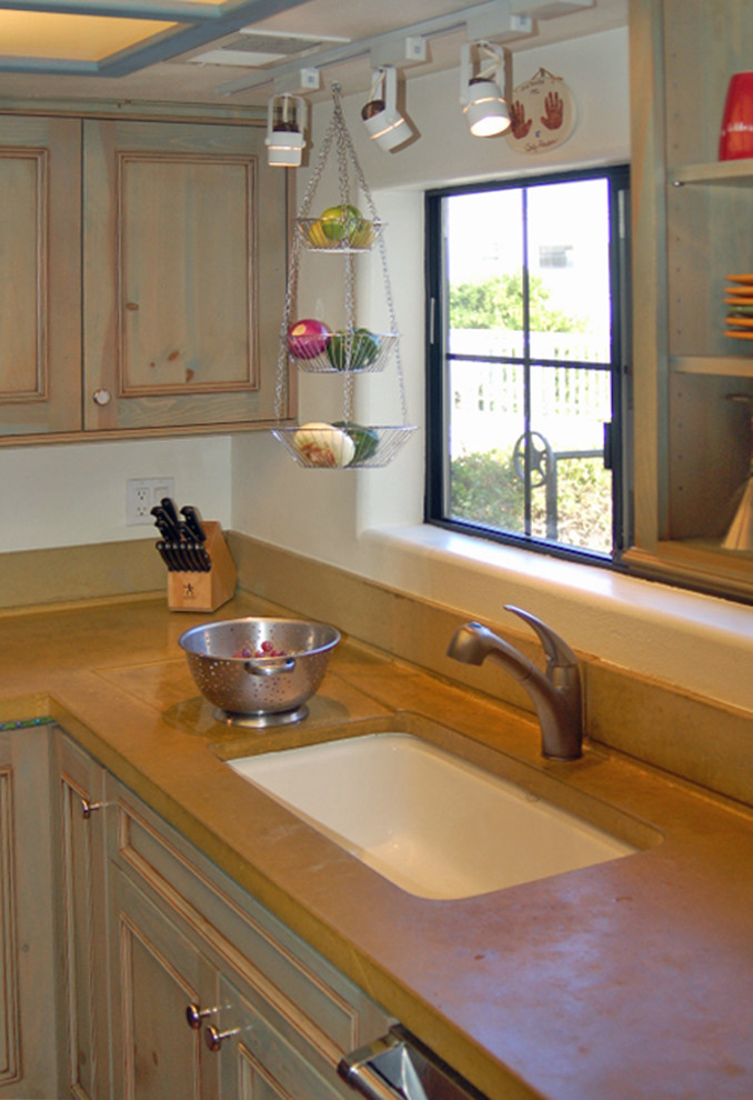 Small country u-shaped separate kitchen in San Luis Obispo with a single-bowl sink, recessed-panel cabinets, green cabinets, concrete benchtops, yellow splashback, stainless steel appliances and terra-cotta floors.