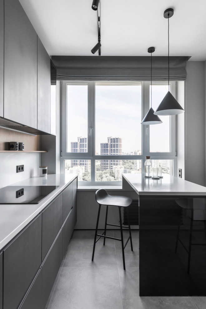 This is an example of a mid-sized contemporary l-shaped eat-in kitchen in Moscow with an undermount sink, flat-panel cabinets, grey cabinets, solid surface benchtops, white splashback, black appliances, porcelain floors, with island, grey floor and white benchtop.