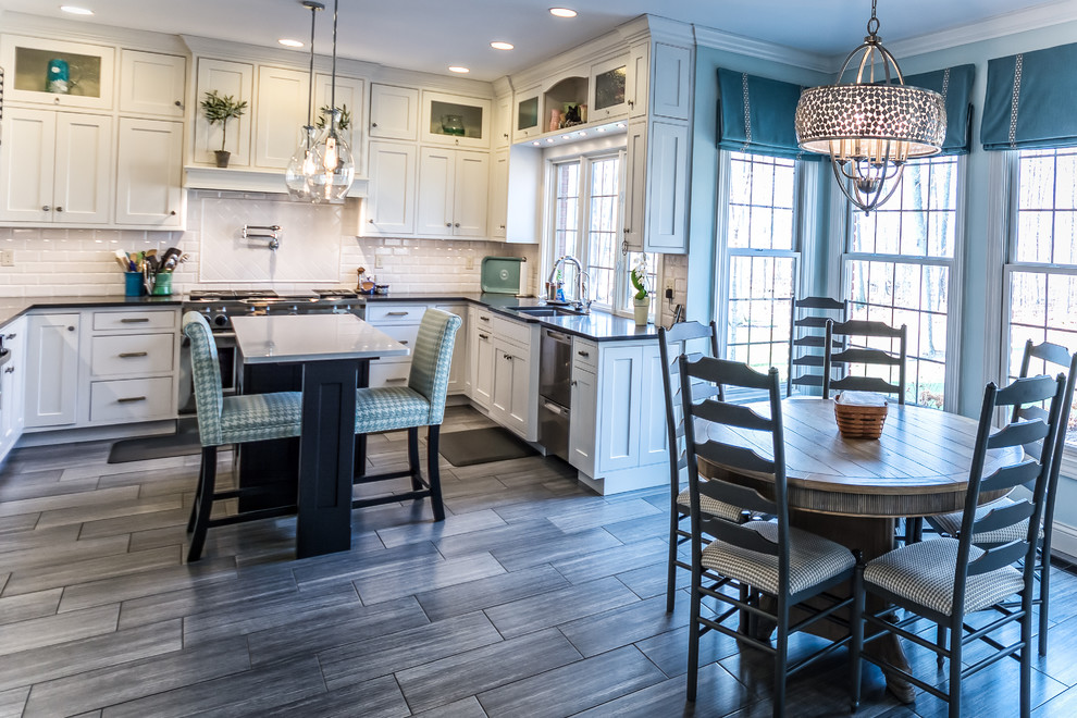 Large transitional u-shaped medium tone wood floor and brown floor eat-in kitchen photo with an undermount sink, shaker cabinets, white cabinets, solid surface countertops, white backsplash, subway tile backsplash, stainless steel appliances and an island