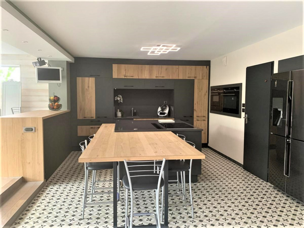 Photo of an expansive single-wall open plan kitchen in Lille with an integrated sink, beaded inset cabinets, grey cabinets, laminate benchtops, black splashback, stainless steel appliances, cement tiles, with island, white floor and brown benchtop.