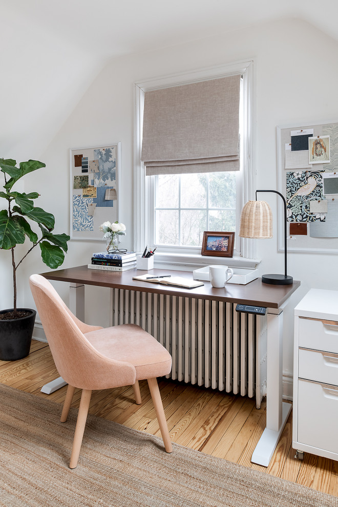 Traditional home office with white walls, light hardwood floors, a freestanding desk, beige floor and vaulted.