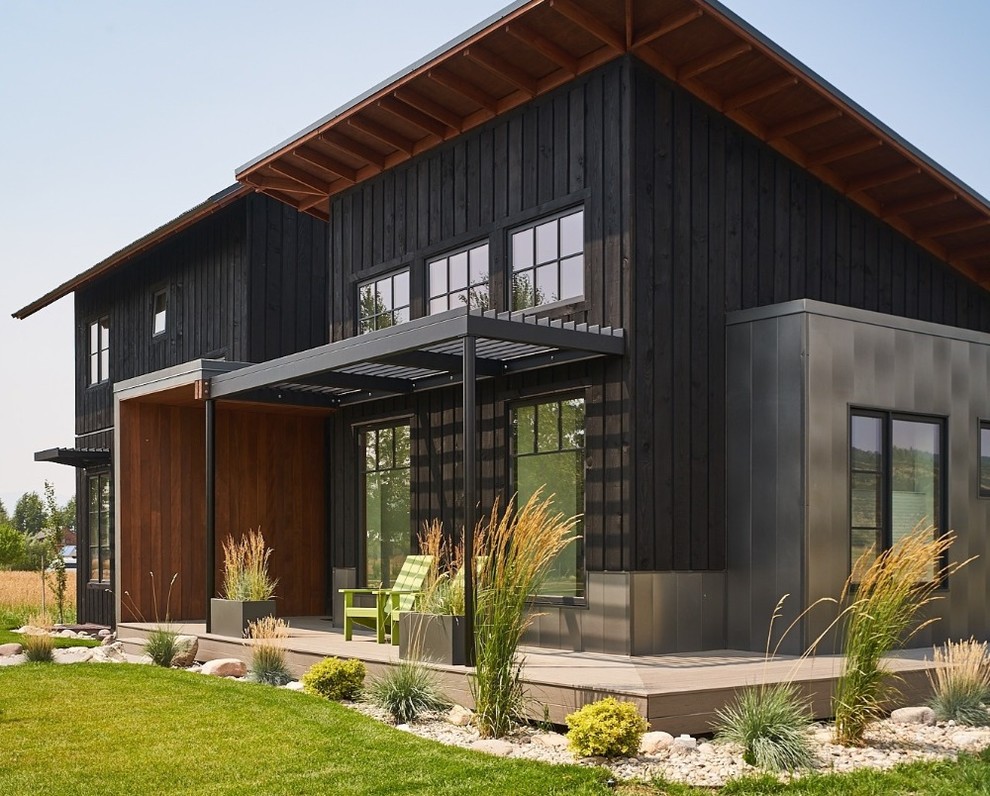 Country two-storey black house exterior in Other with wood siding and a metal roof.