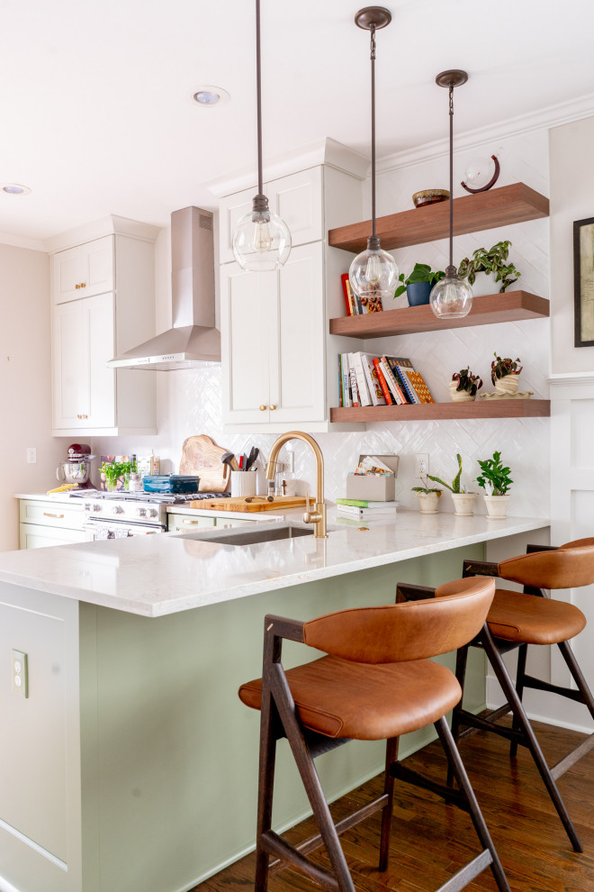 Photo of a small eclectic l-shaped eat-in kitchen in Atlanta with a single-bowl sink, shaker cabinets, green cabinets, quartz benchtops, white splashback, ceramic splashback, stainless steel appliances, medium hardwood floors, a peninsula, brown floor and multi-coloured benchtop.