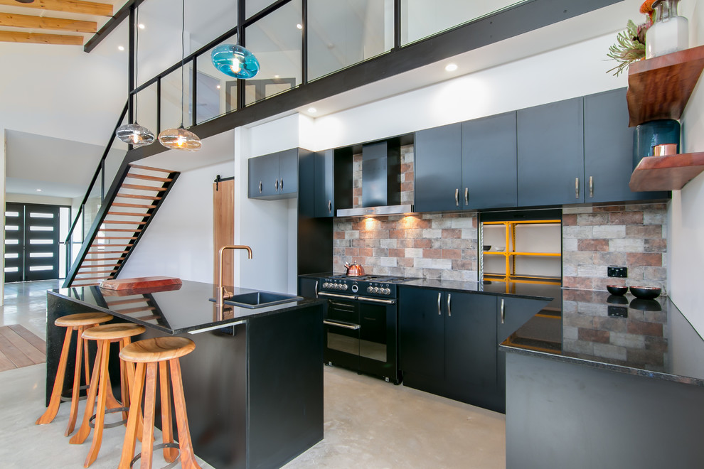 Inspiration for a large contemporary l-shaped eat-in kitchen in Cairns with a drop-in sink, beaded inset cabinets, black cabinets, granite benchtops, multi-coloured splashback, ceramic splashback, black appliances, concrete floors and with island.