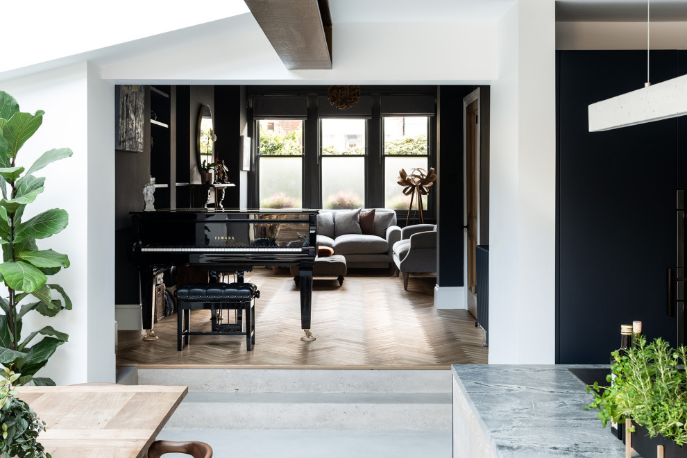 This is an example of a mid-sized contemporary open concept living room in London with black walls, medium hardwood floors, a standard fireplace and exposed beam.