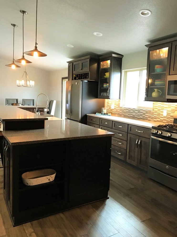 Open concept kitchen - mid-sized transitional single-wall light wood floor and brown floor open concept kitchen idea with shaker cabinets, dark wood cabinets, multicolored backsplash, glass tile backsplash, stainless steel appliances, an island, a farmhouse sink and granite countertops