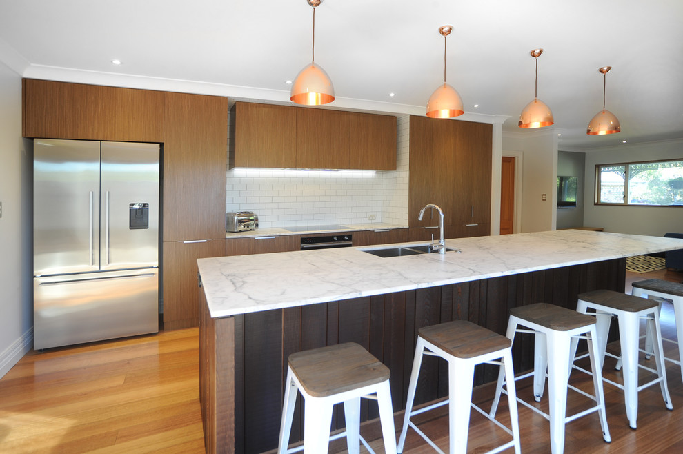 Design ideas for a mid-sized modern galley eat-in kitchen in Auckland with an undermount sink, flat-panel cabinets, medium wood cabinets, marble benchtops, white splashback, subway tile splashback, stainless steel appliances, medium hardwood floors and with island.